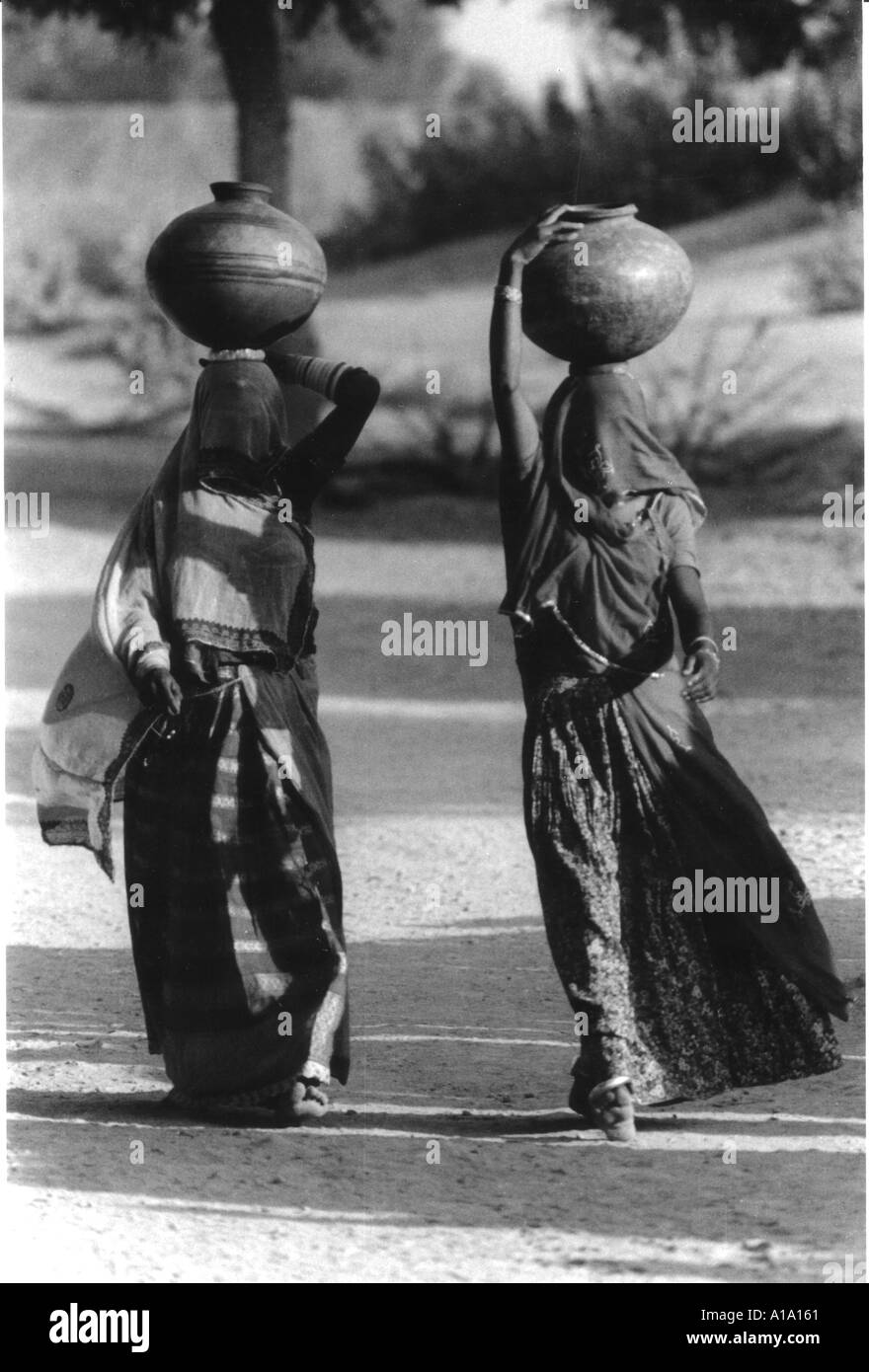 Visages couverts mesdames avec des pots sur la tête aller au puits du village pour aller chercher de l'eau dans le Rajasthan en Inde Banque D'Images