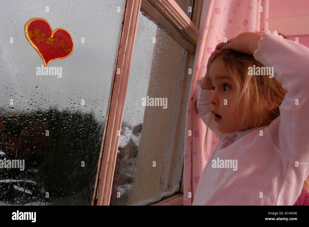 Jeune fille à la recherche de la fenêtre de la chambre à la neige, à l'extérieur. Banque D'Images