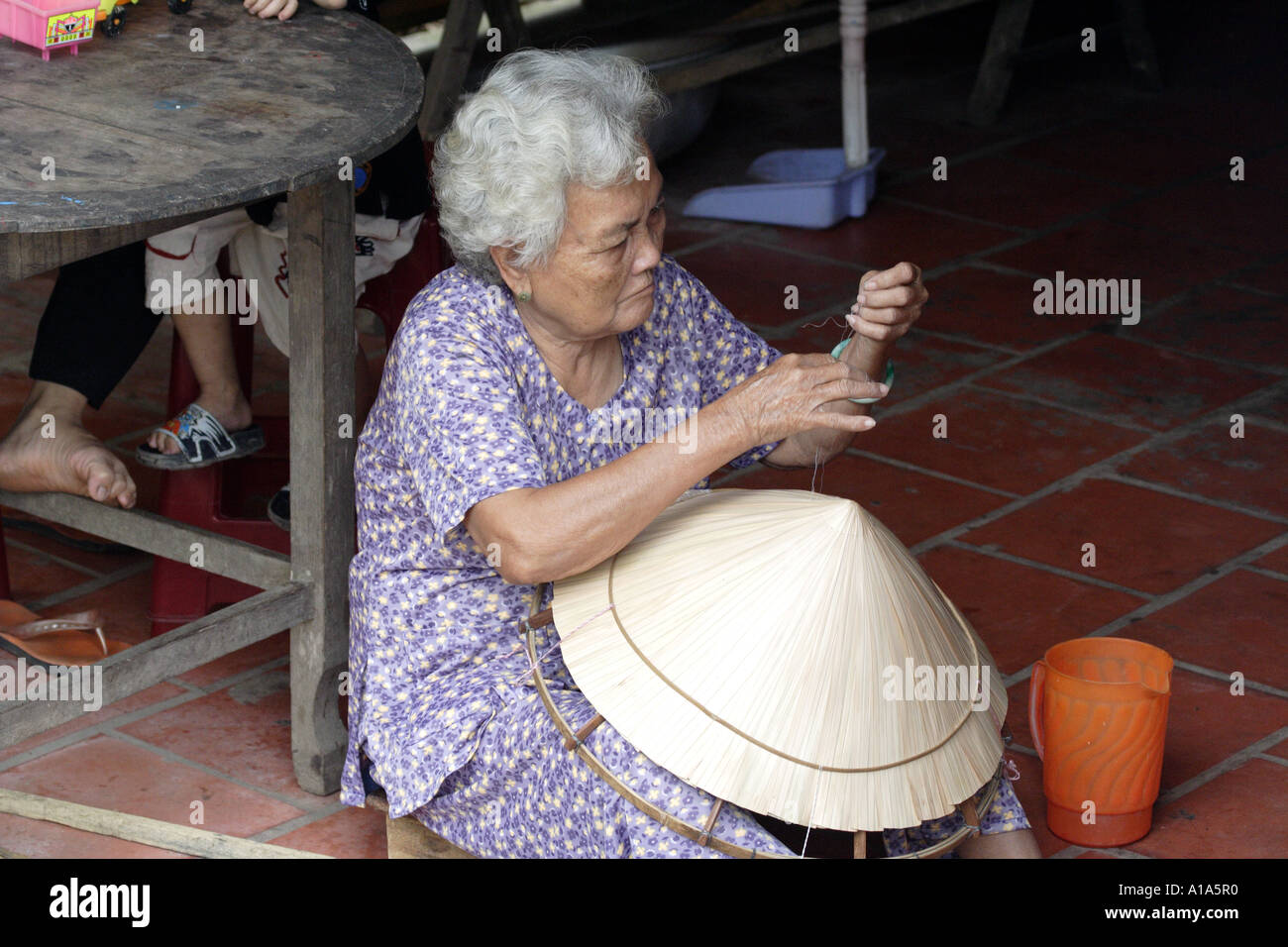 Femme âgée la couture d'un chapeau traditionnel, Delta du Mékong, Vietnam Banque D'Images