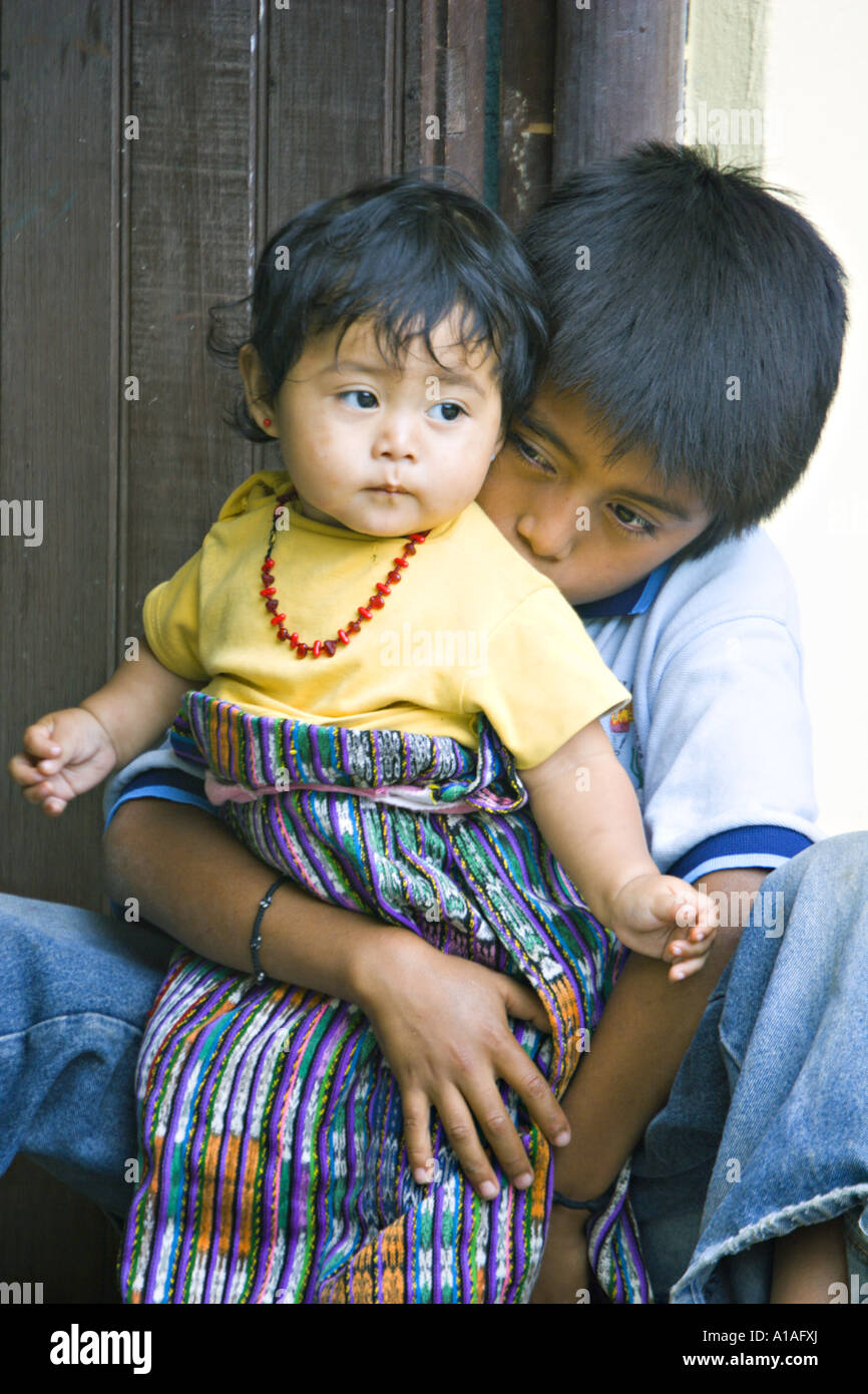 GUATEMALA SAN PEDRO LA LAGUNA peuples mayas Tzutujil garçon babysits sa soeur qui le porte bébé tissé à la traditionnelle corte Banque D'Images