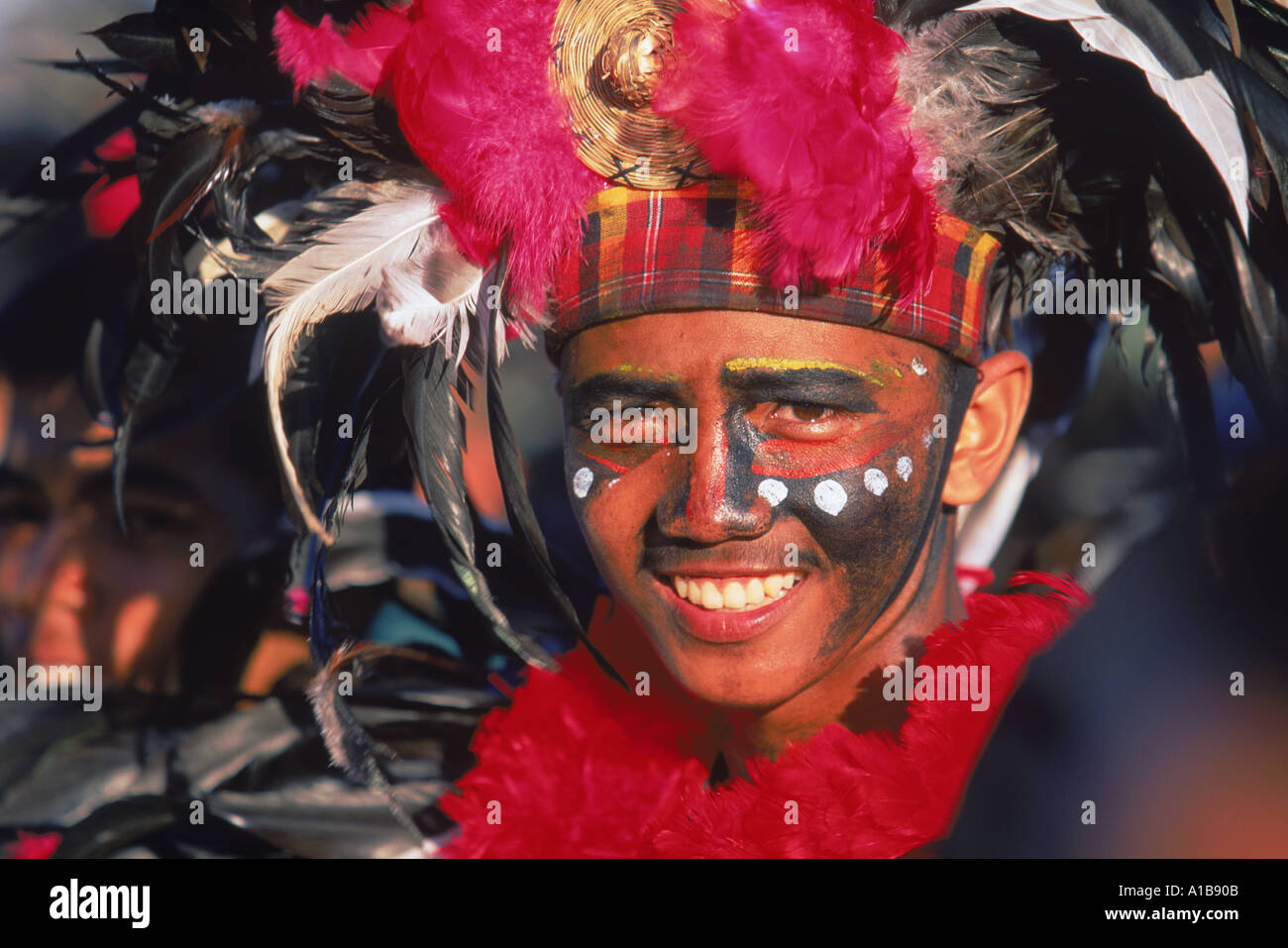Portrait d'un homme avec la décoration du visage et de la tête avec des plumes robe à Mardi Gras carnival Dinagyang à Iloilo City sur Panay Banque D'Images