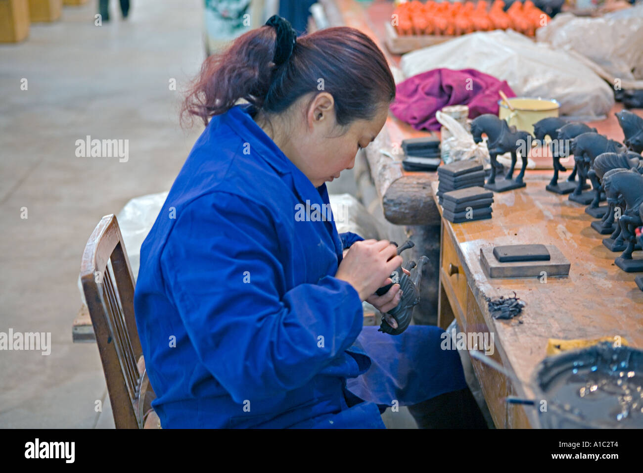 La CHINE XI'AN femme artiste chinois ajout de détails à des modèles d'argile de chevaux sur le site de l'Armée de terre cuite à Xi'an Banque D'Images
