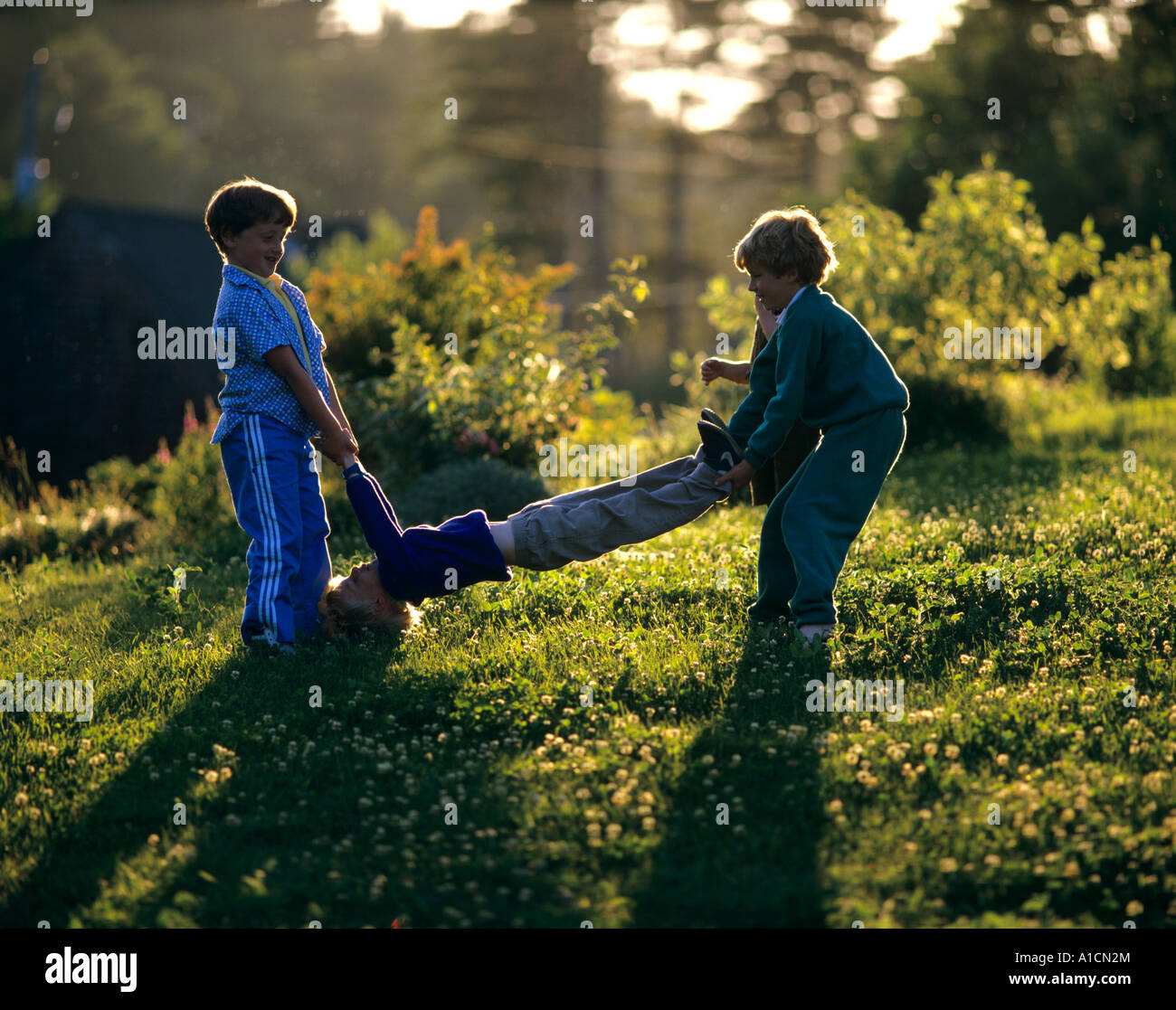 Trois jeunes garçons jouant dans la cour. Deux garçons sont la troisième se balançant d