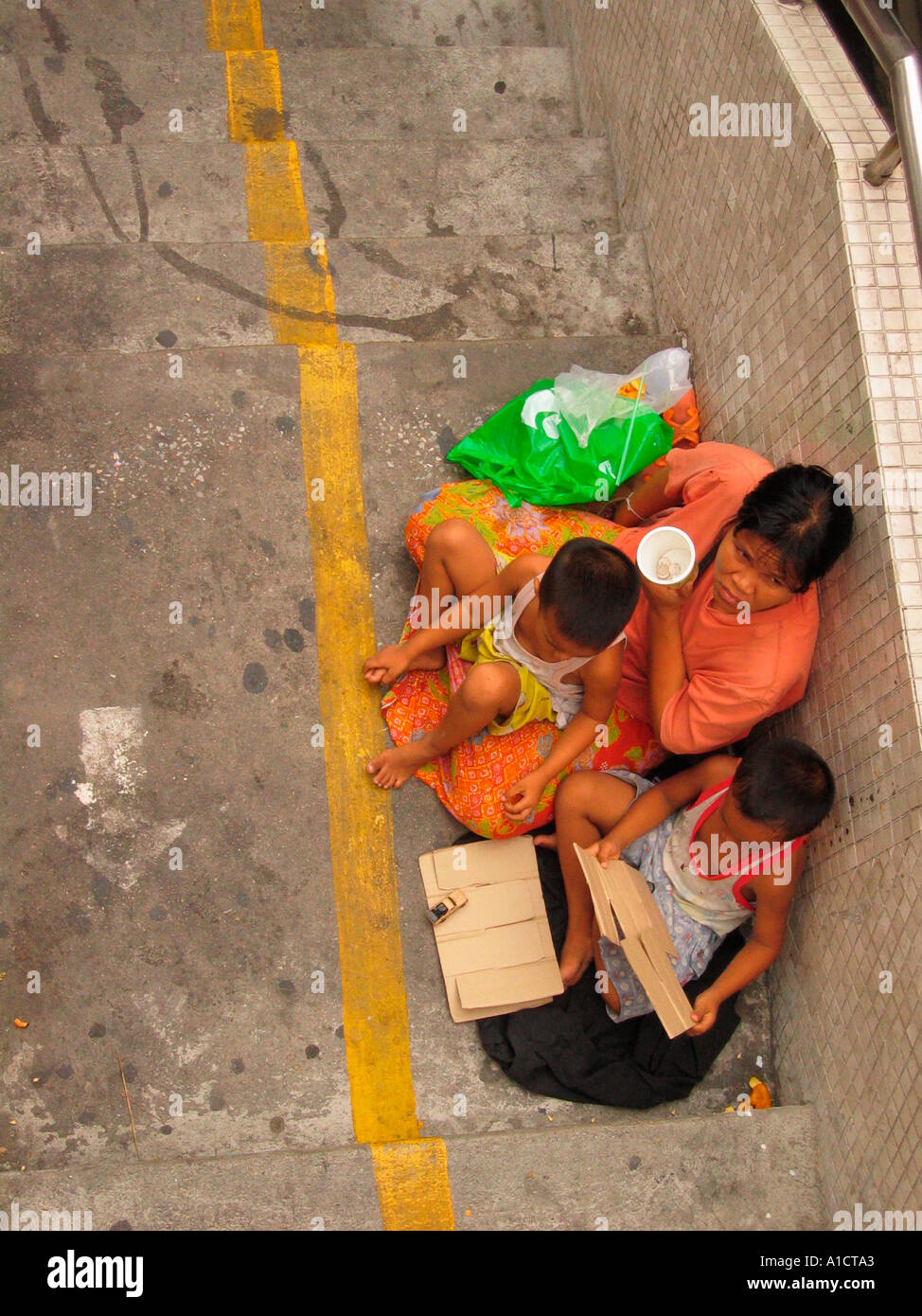 Femme deux enfants mendier avec tasse sur Sukhumvit Road, Bangkok Thaïlande pont piétonnier Banque D'Images