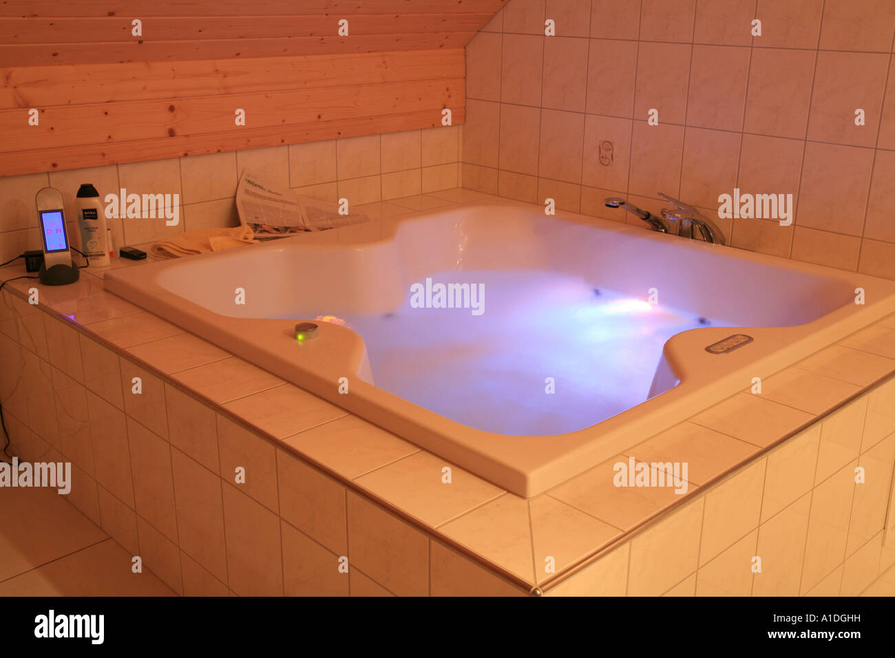 Jacuzzi à remous avec télécommande et lumières colorées dans une salle blanche Banque D'Images