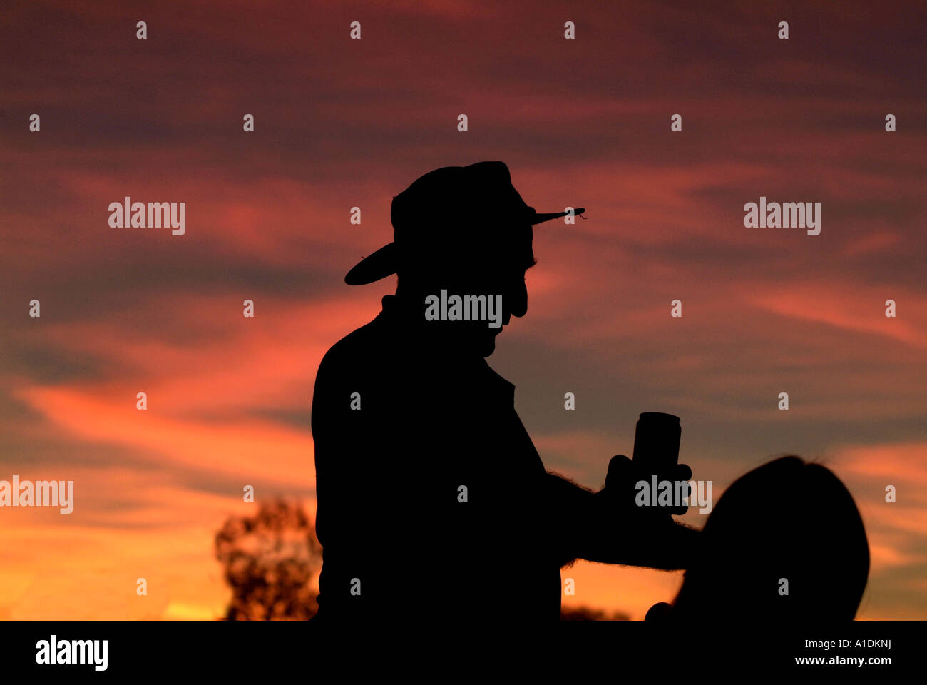 Un agriculteur qui se profile au coucher du soleil avec un ciel orange photo par Bruce Miller Banque D'Images