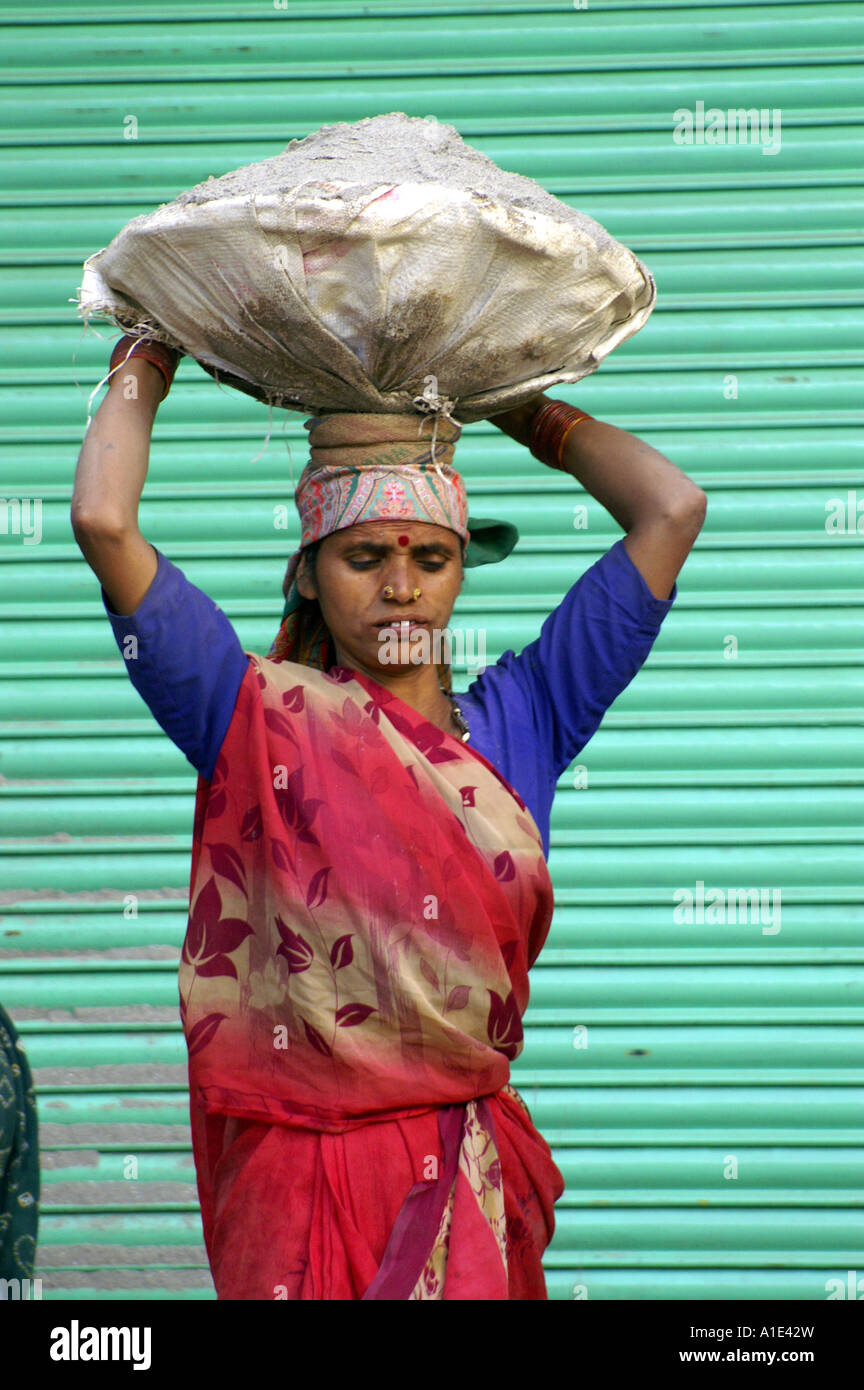 Vieille Femme indienne en sari rouge travaillant dur manuellement sur site de construction Banque D'Images