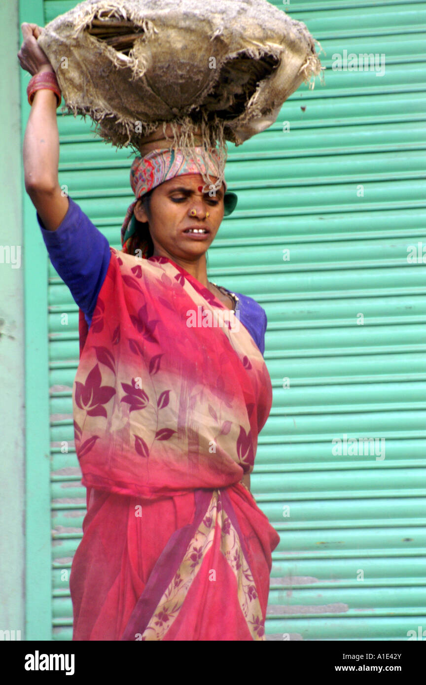 Vieille Femme indienne en sari rouge travaillant dur manuellement sur site de construction en Inde Banque D'Images