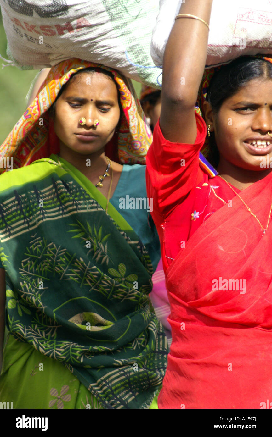Équipe deux femmes indiennes en sari coloré travaillant dur de porter de lourds sacs de sable à la construction de la rue, de l'Inde site Banque D'Images