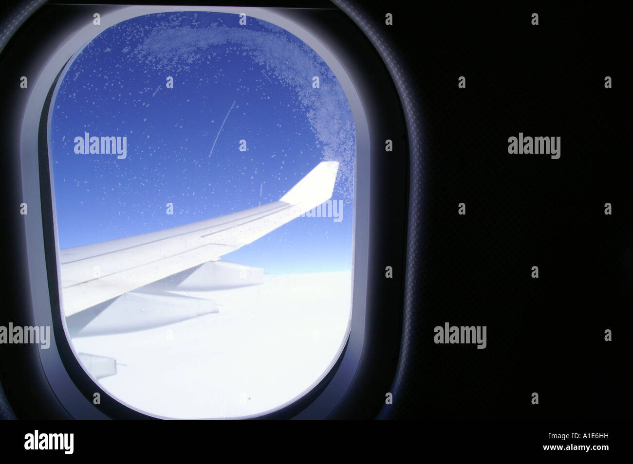 Fenêtre ronde d'airbus avion aile d'avion au-dessus des nuages lumineux blanc épais et ciel bleu azur haute altitude Banque D'Images