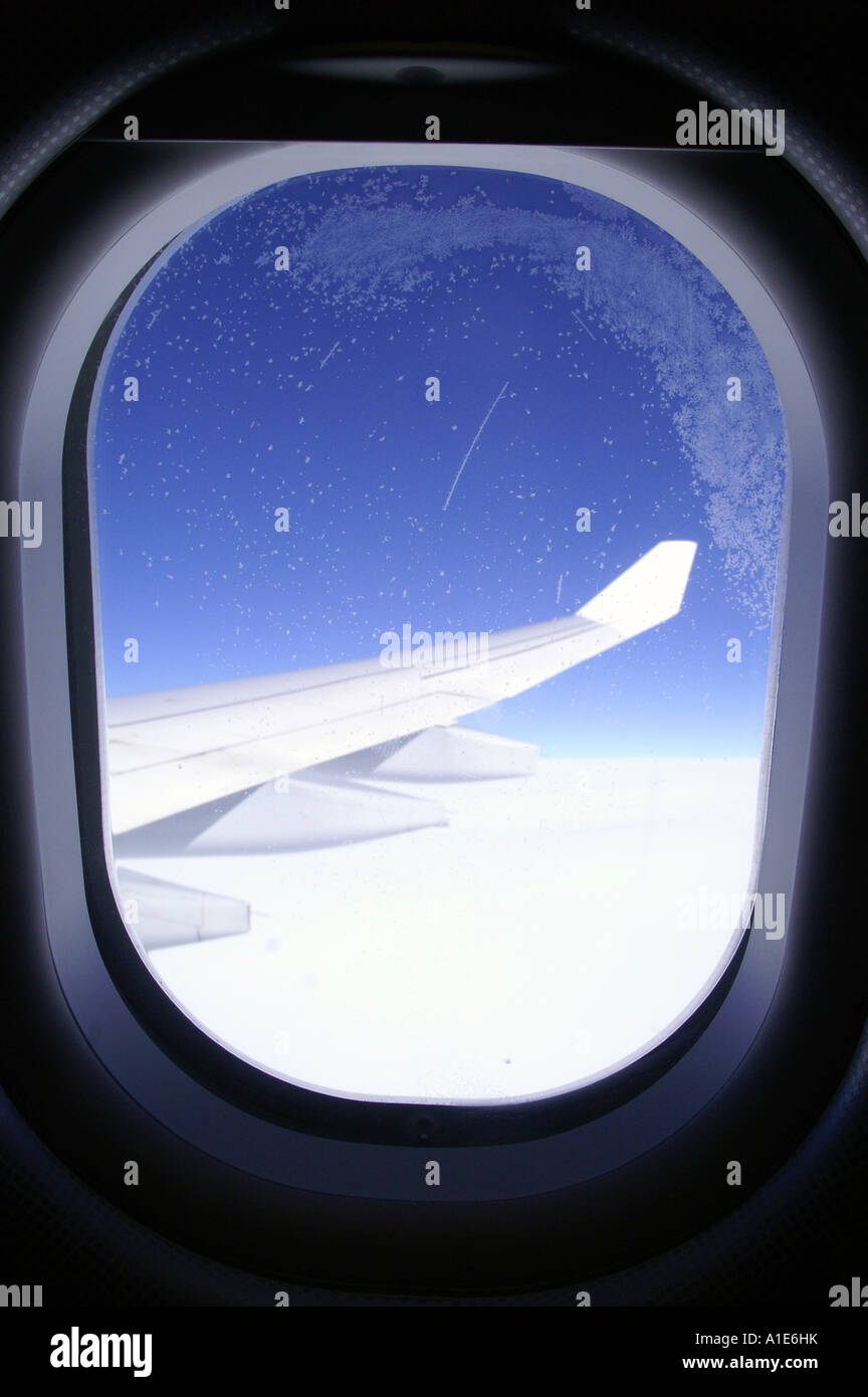 Fenêtre ronde d'airbus avion aile d'avion au-dessus des nuages lumineux blanc épais et ciel bleu azur haute altitude Banque D'Images