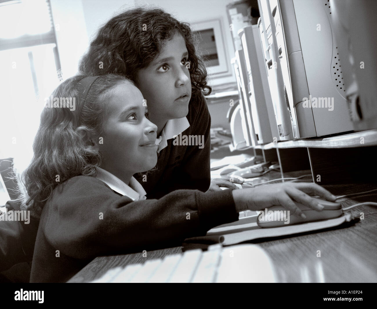 Deux écolières junior travaillent ensemble sur leur ordinateur dans l'école moderne et spacieuse salle de classe informatique Banque D'Images