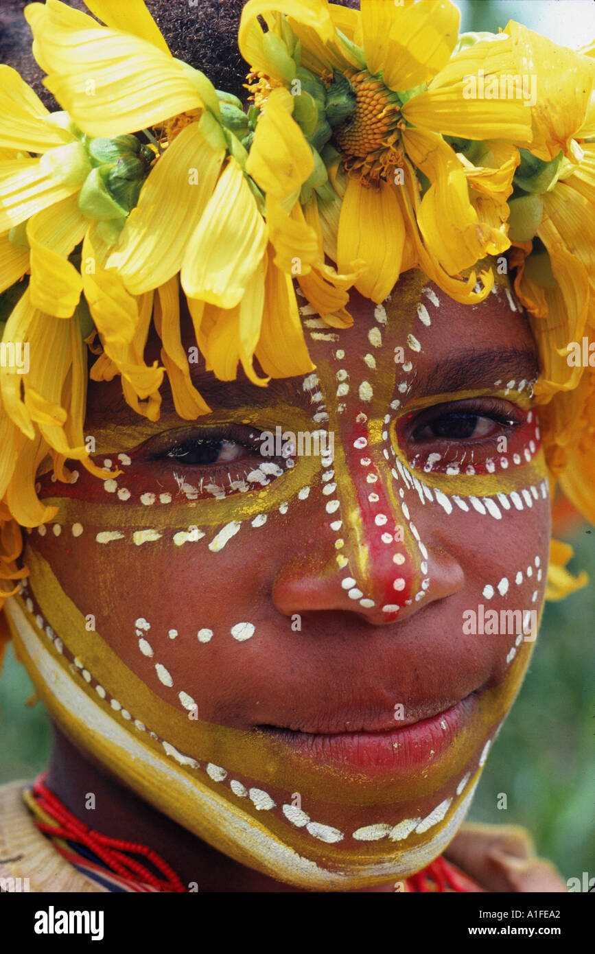 Portrait d'un enfant avec la décoration du visage et portant des fleurs jaunes dans leurs cheveux en Papouasie Nouvelle Guinée, Îles du Pacifique M Banque D'Images