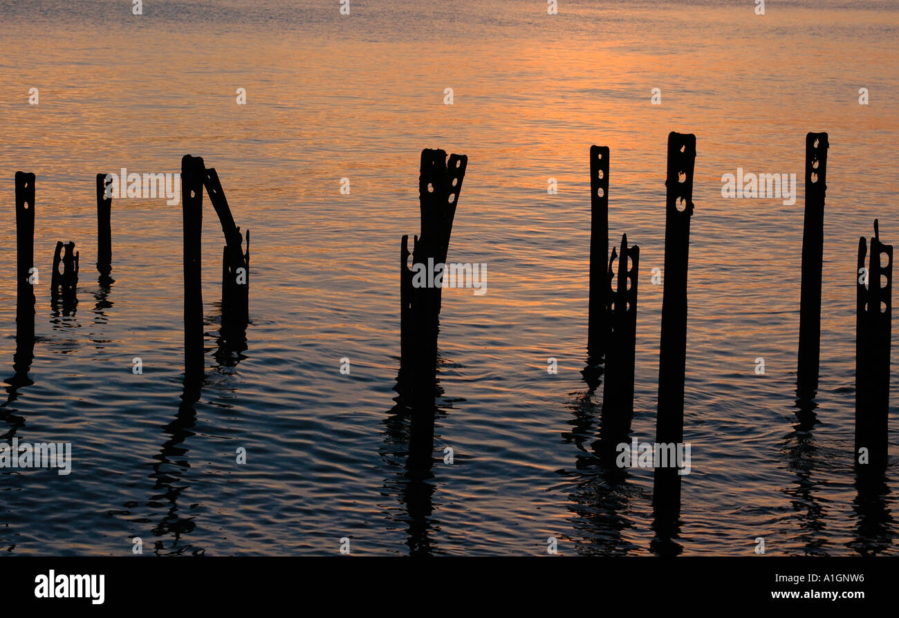 Fer rouille posts contre un ciel du soir se reflètent dans la mer. Banque D'Images