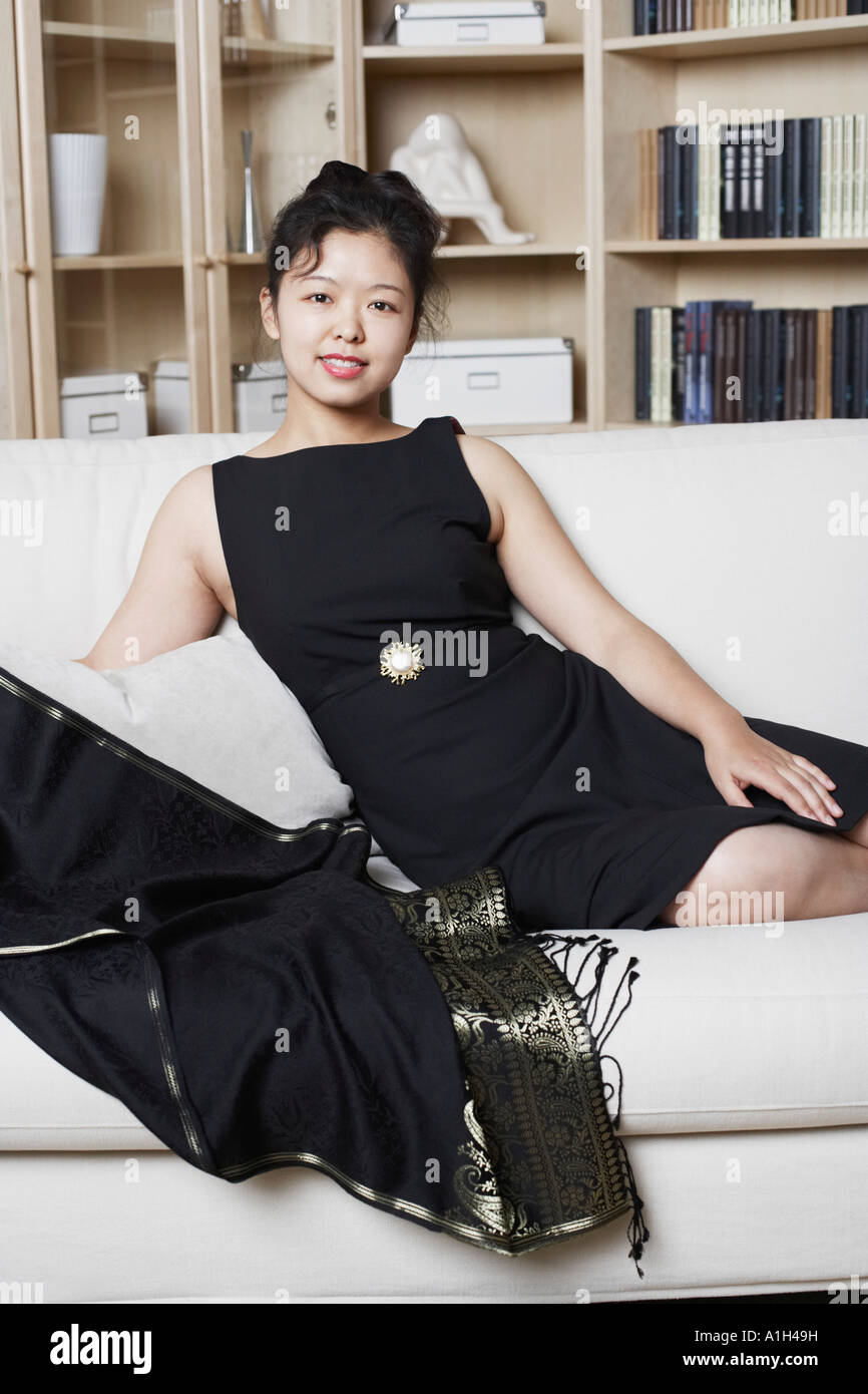 Portrait of a young woman sitting on a couch smiling Banque D'Images