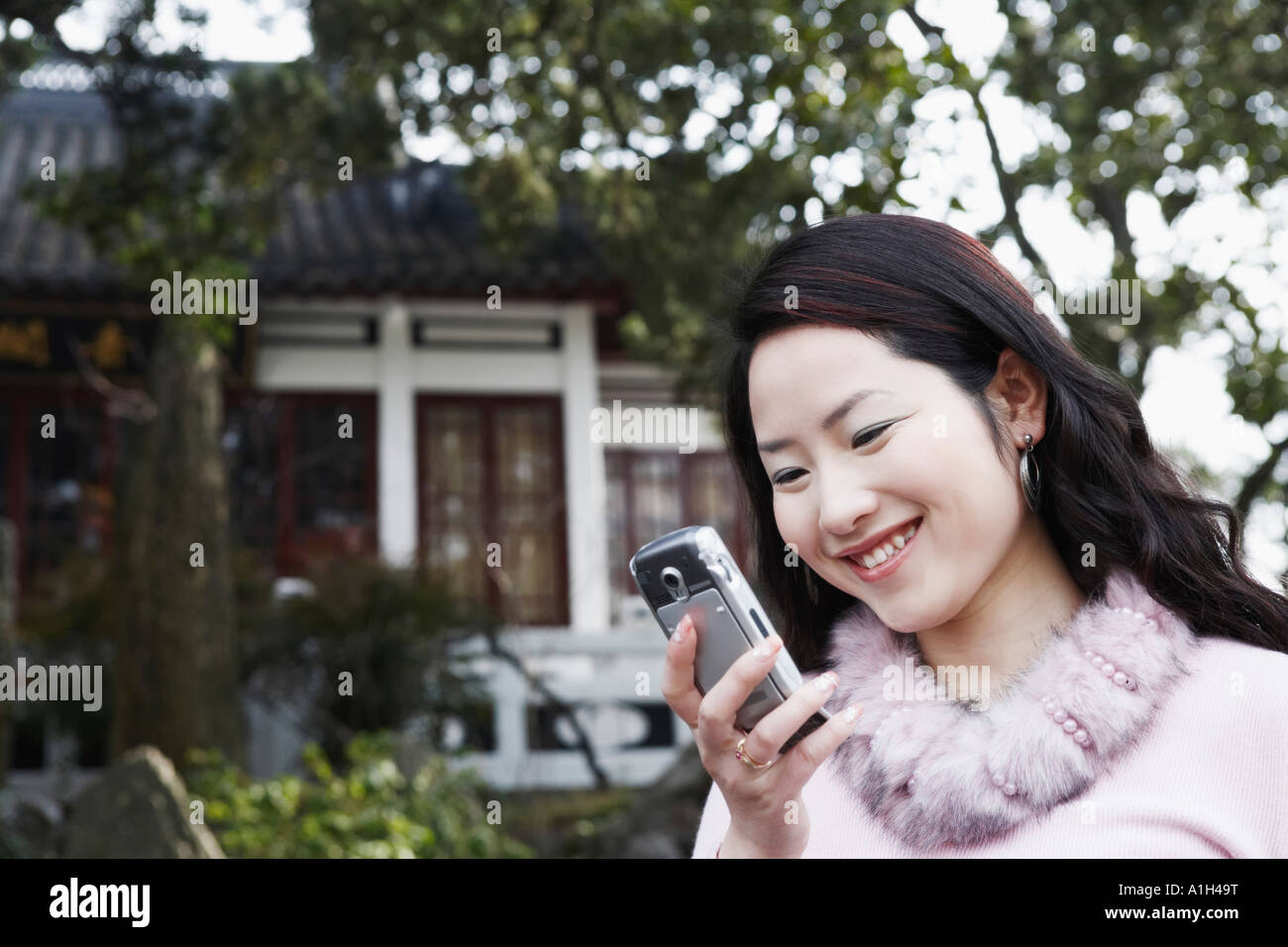 Close-up of a young woman looking at a mobile phone smiling Banque D'Images