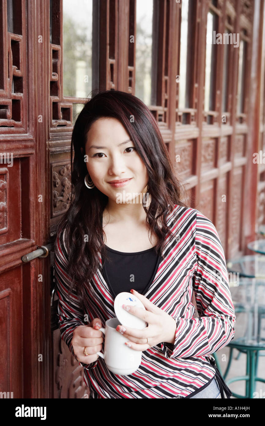 Portrait d'une jeune femme tenant une tasse avec un couvercle smiling Banque D'Images