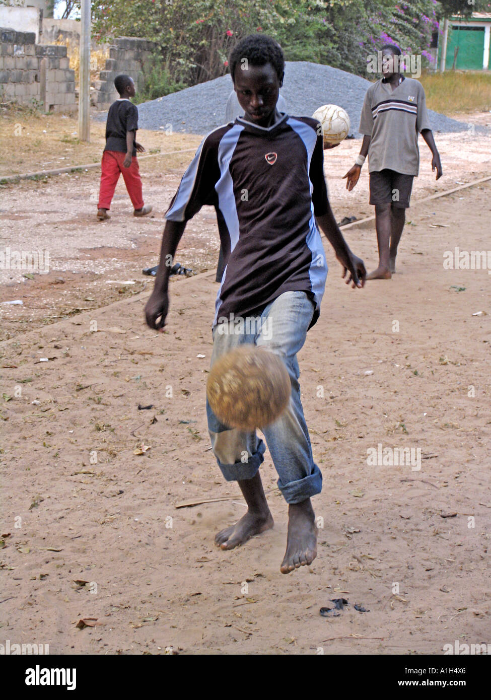 Les garçons jouent au football pieds nus dans la poussière de la Gambie Bakau Banque D'Images