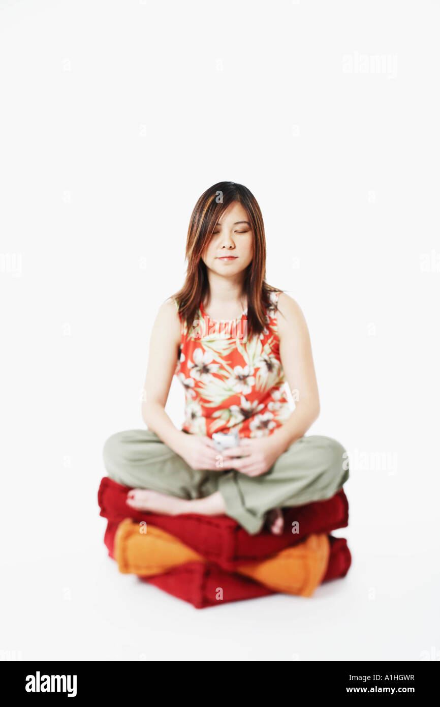 Mid adult woman sitting on coussins avec ses yeux fermés Banque D'Images