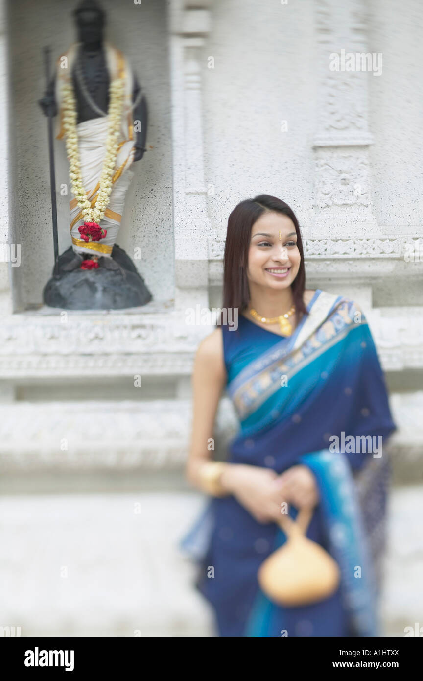 Jeune femme debout devant une figure religieuse Banque D'Images