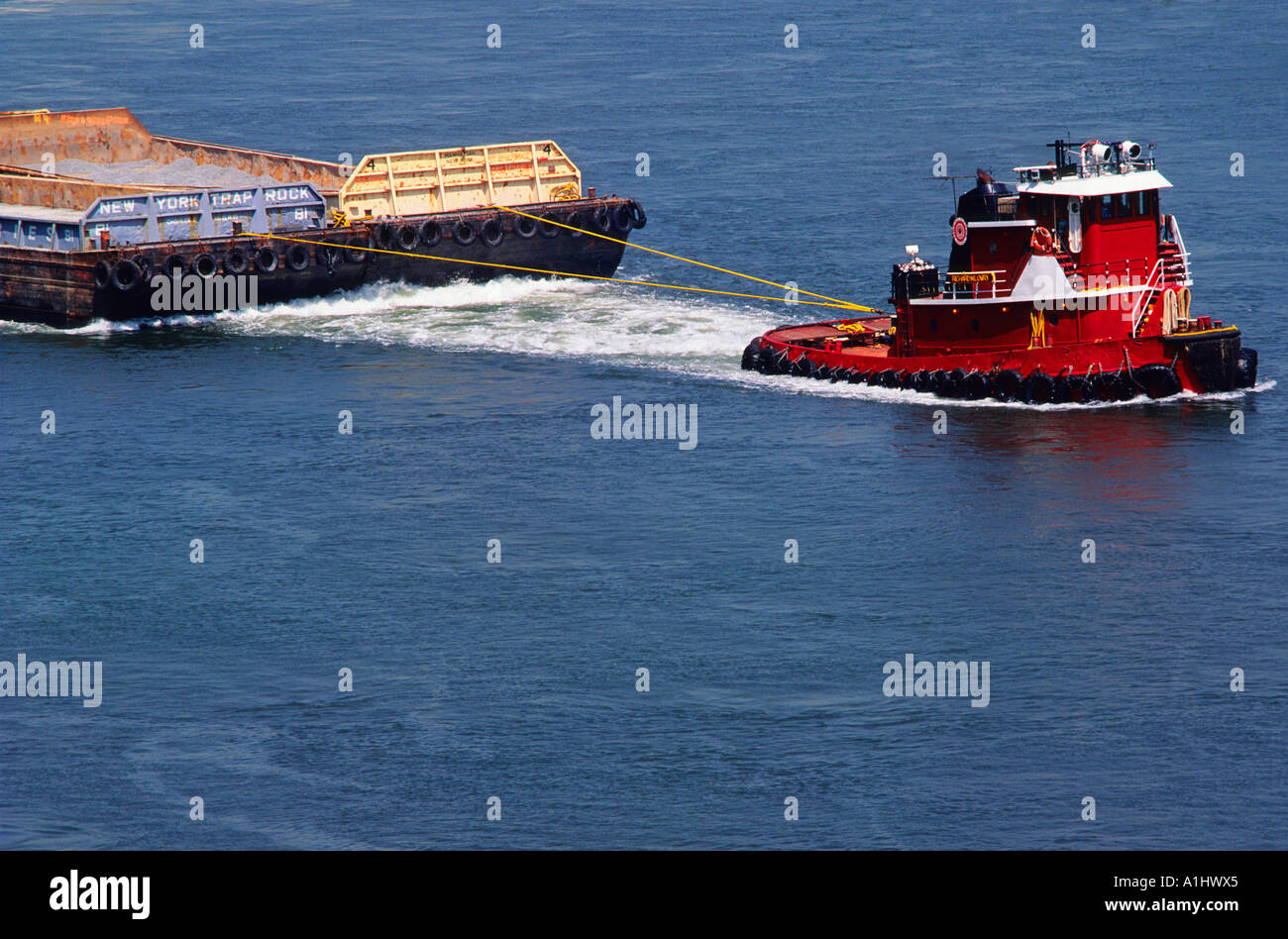 Remorqueur ou remorqueur remorquant une barge ou une scierie chargée. East River, New York, États-Unis. Vue rapprochée d'un navire de mer relié à une barge plate Banque D'Images