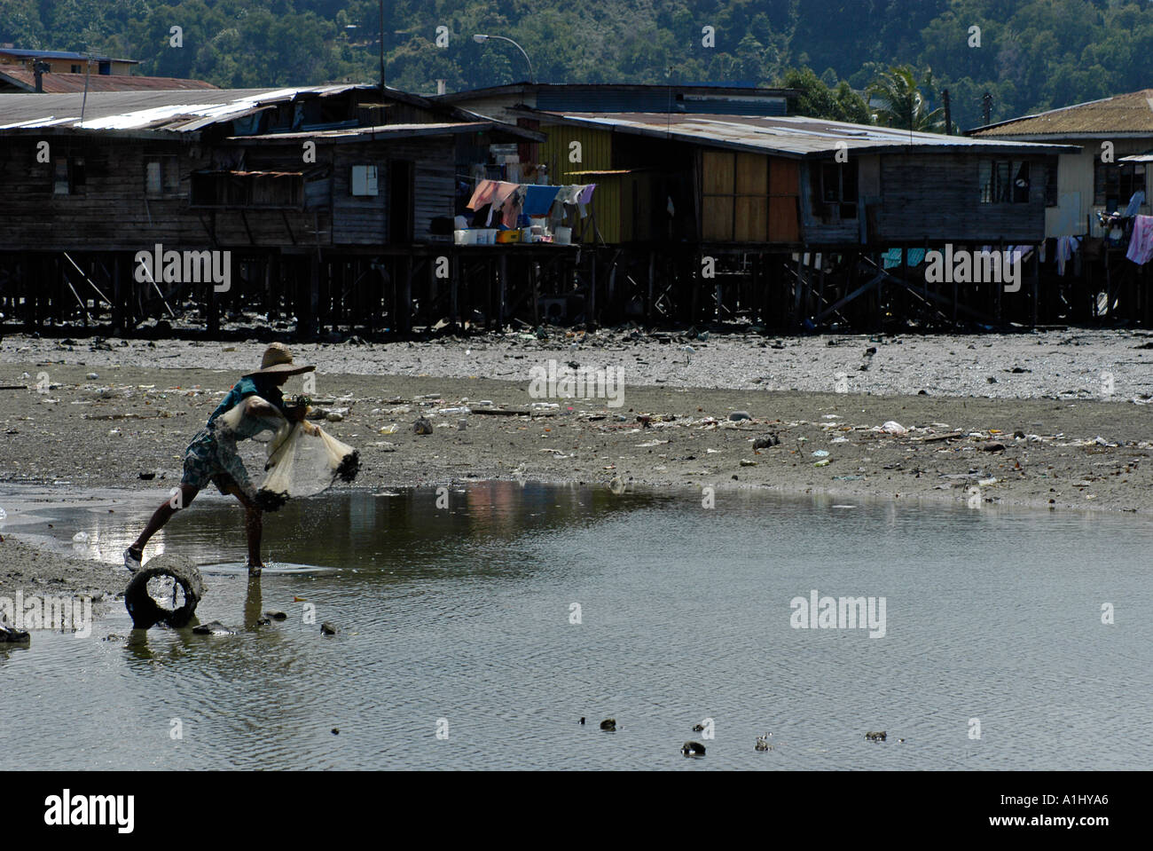 Casting pêcheur malaisien filet devant l'eau du village. Partie d'une séquence. Banque D'Images