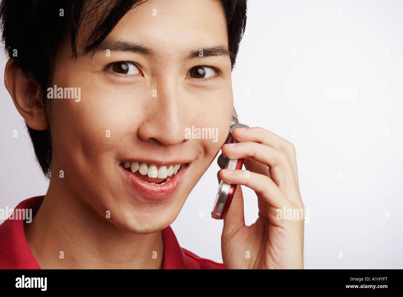 Portrait of a young man smiling and talking on a mobile phone Banque D'Images