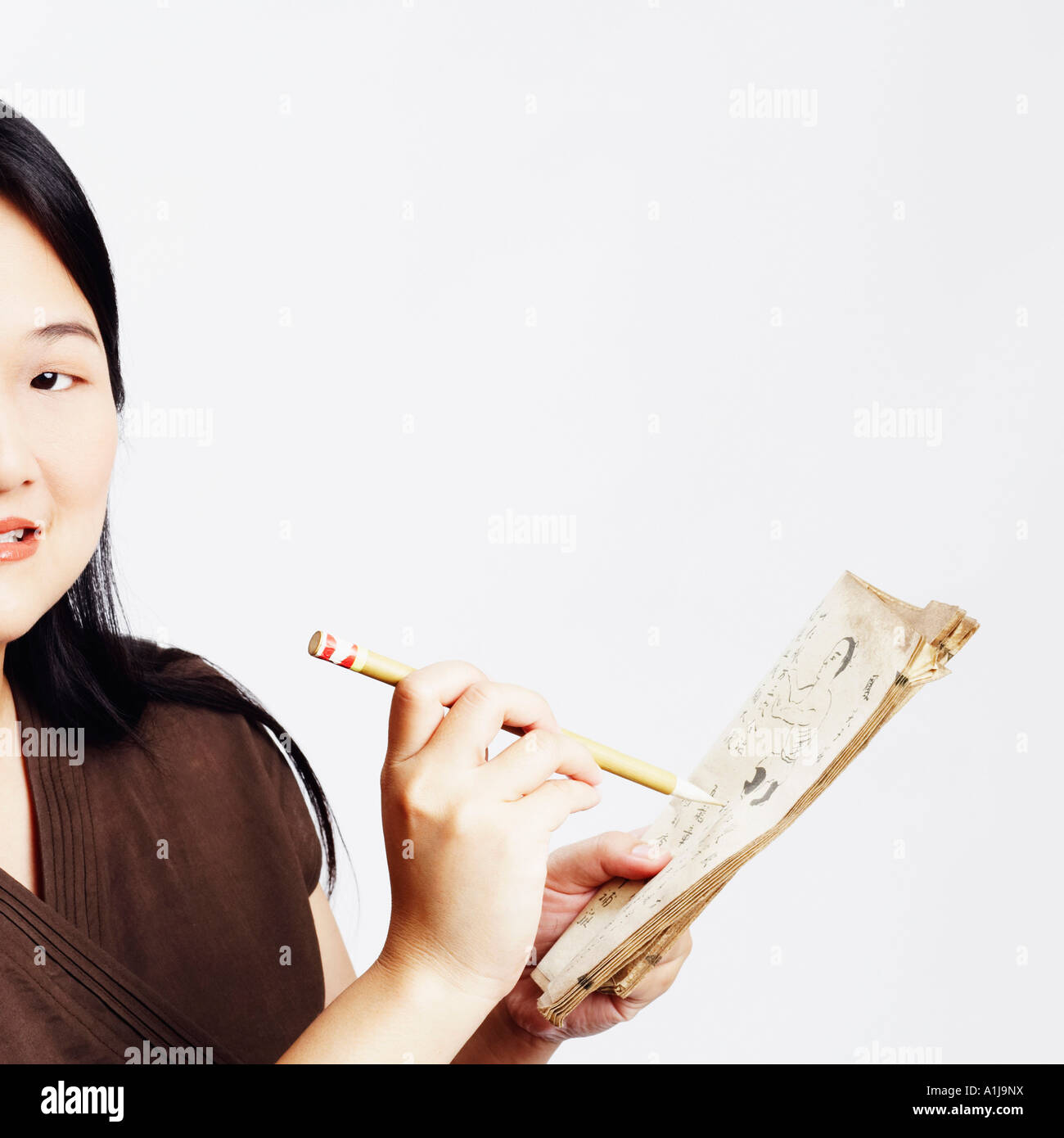 Portrait of a Mid adult woman holding un crayon avec un livre et smiling Banque D'Images