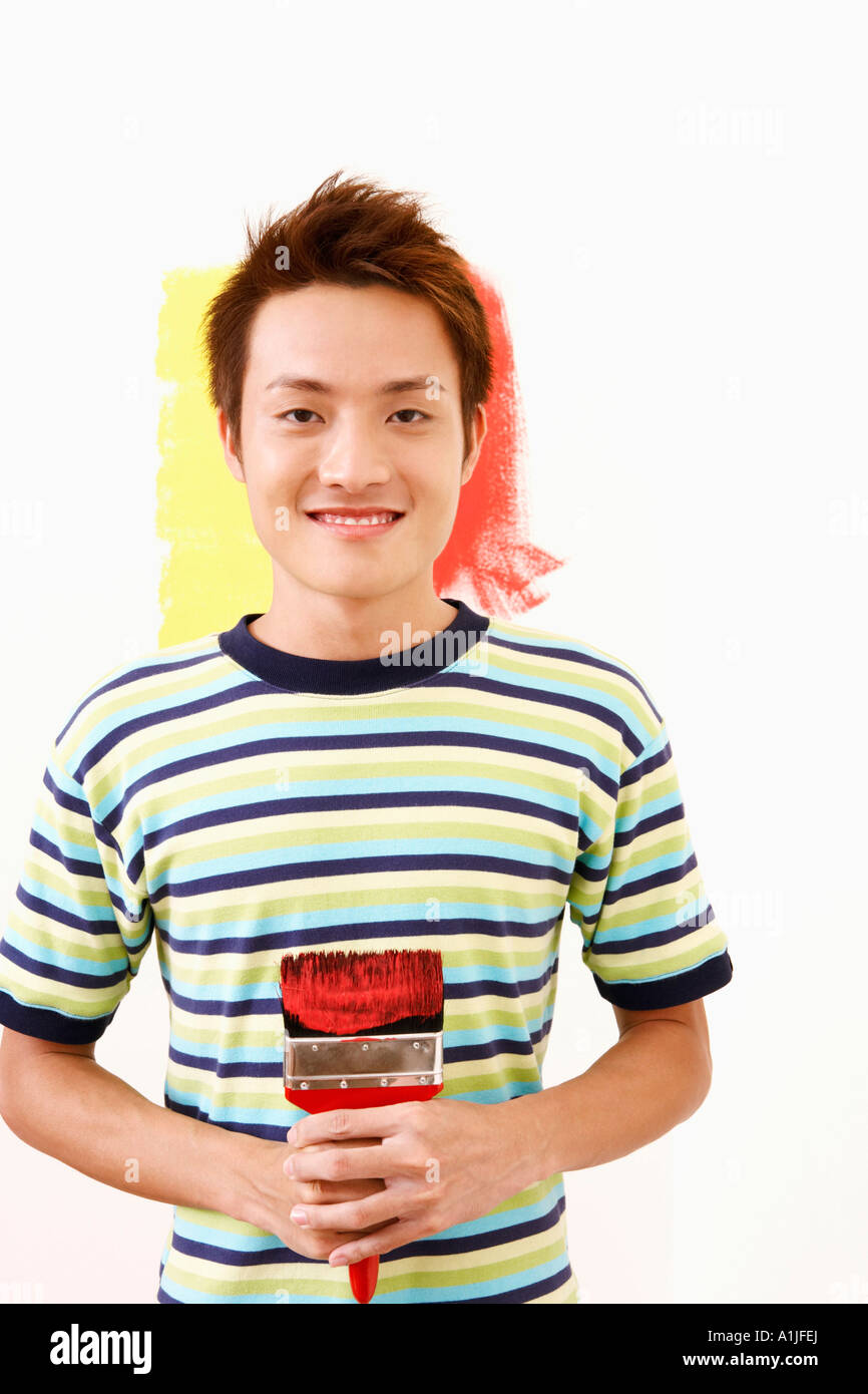 Portrait of a young man holding a paintbrush and smiling Banque D'Images