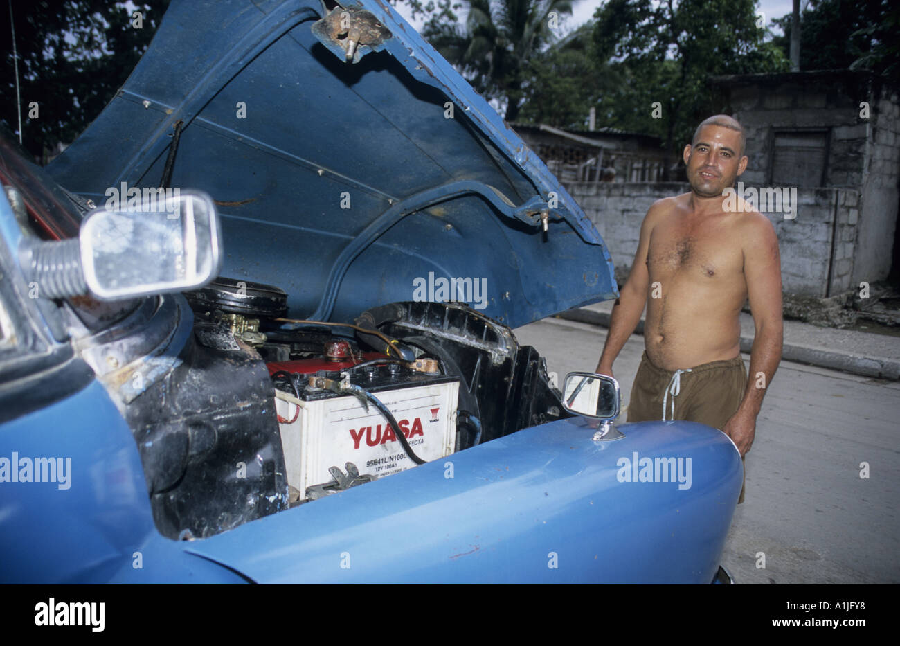 Cuba. Un fier propriétaire d'un American oldtimer bleu montre le moteur sous le capot Banque D'Images