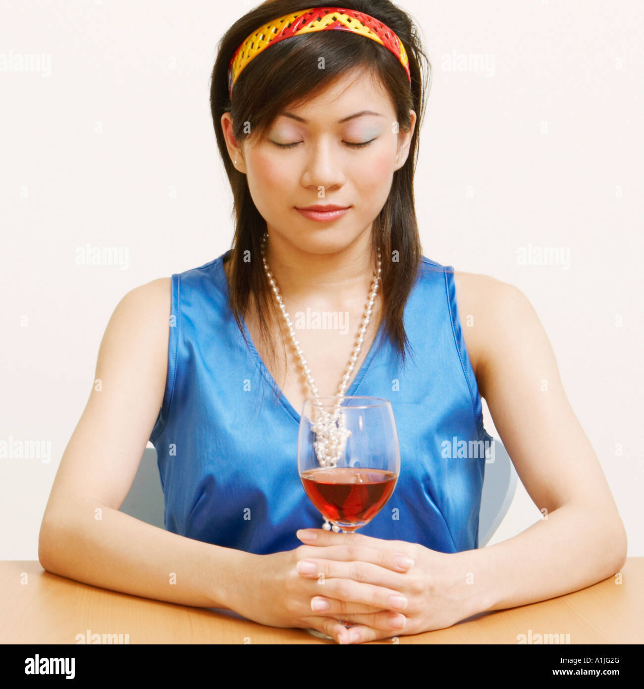 Portrait d'une jeune femme tenant un verre de vin avec ses yeux fermés Banque D'Images