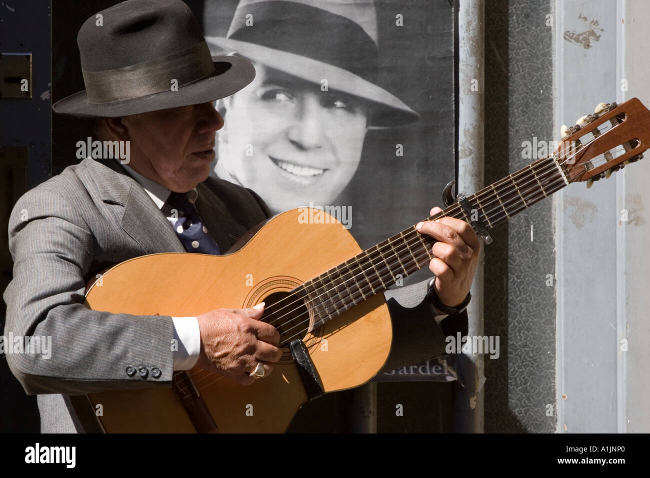 Vieil homme jouant avec la guitare sur le trottoir (en face de photo de Carlos Gardel) un Banque D'Images