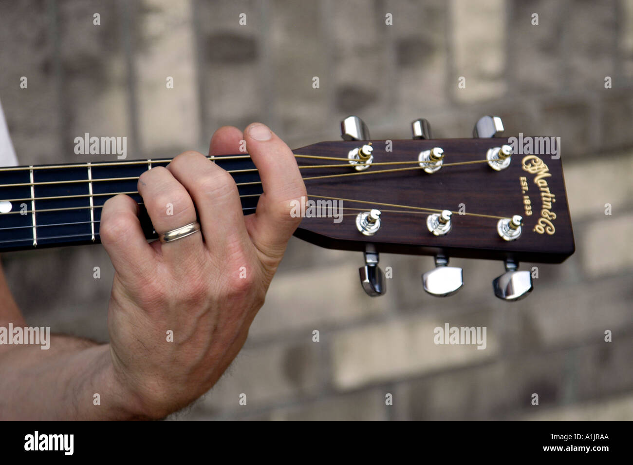 Close up de race blanche main gauche avec anneau de mariage sur l'un des  diagrammes guitare acoustique Martin Photo Stock - Alamy