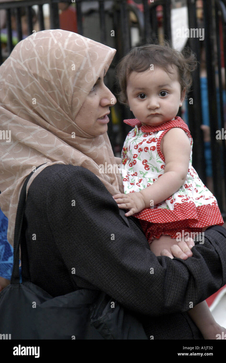 Camera Bebe Regarde Comme Elle S Effectue Dans Les Bras De Mere Portant Le Hijab La Marche A Mi Chemin Du Festival International Arabe Photo Stock Alamy
