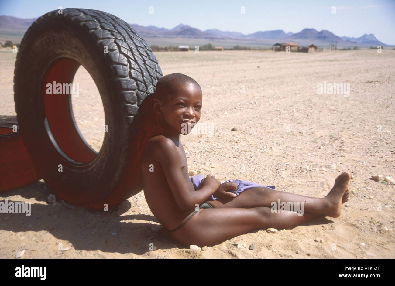 Jeune garçon Herero avec de vieux pneus à Purros village dans la région nord ouest de la Namibie Kaokoveld Afrique Les Herero s'habiller composé d Banque D'Images