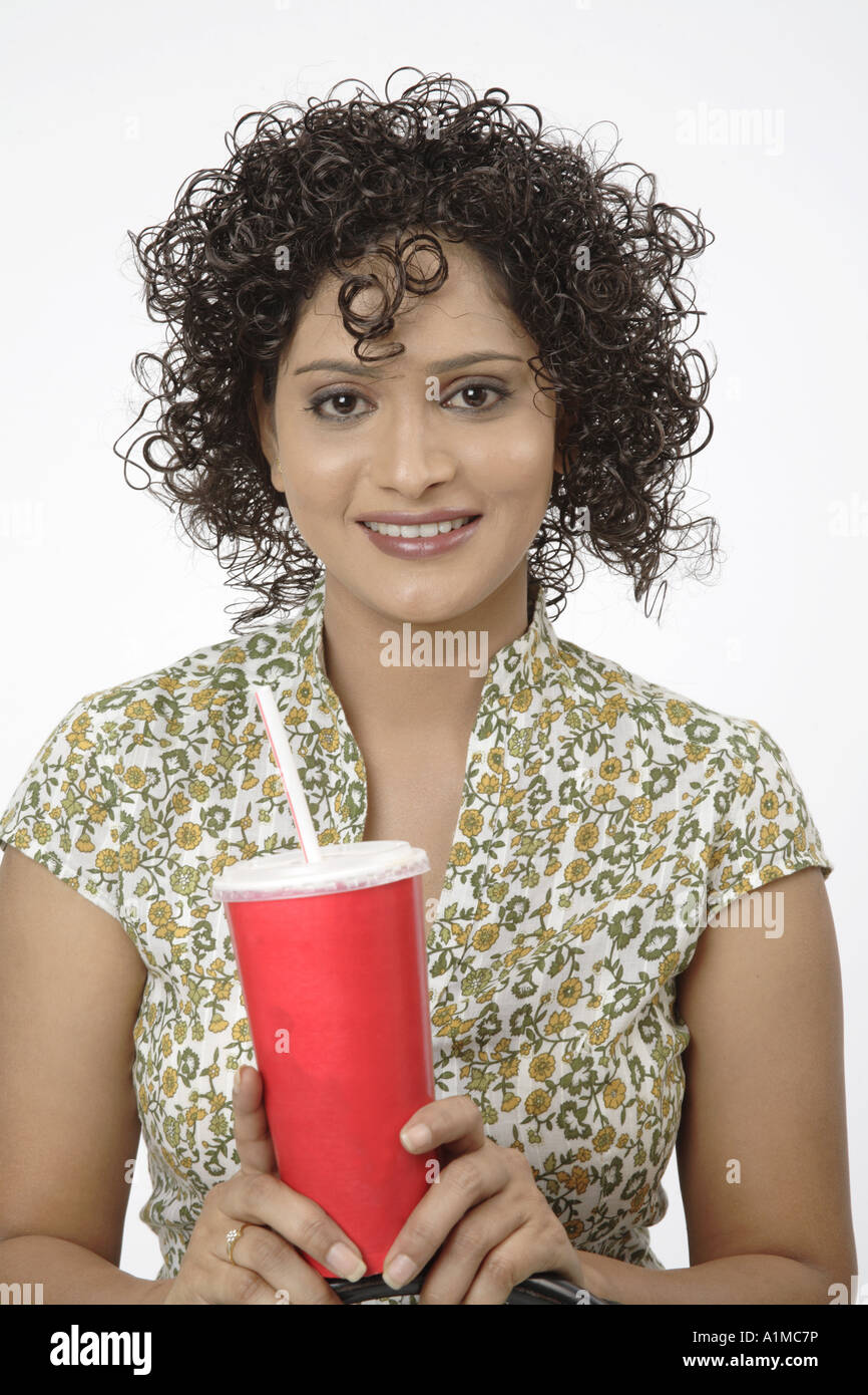 Heureux adolescent indien avec open hair et boisson froide dans sa main Banque D'Images