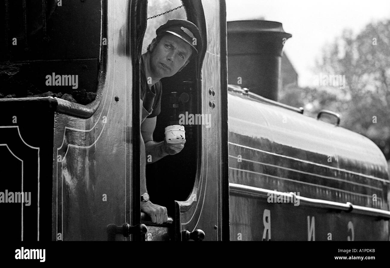 L'homme à sortir de la cabine de conduite d'une petite locomotive à vapeur des réservoirs latéraux. Banque D'Images