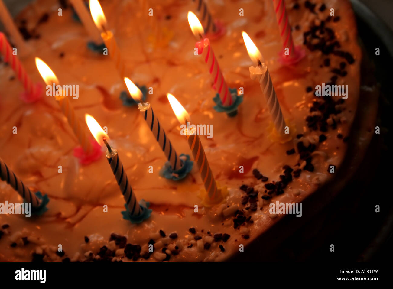 Gâteau d'anniversaire avec bougies allumées, garniture de caramel et saupoudrées de chocolat. Banque D'Images