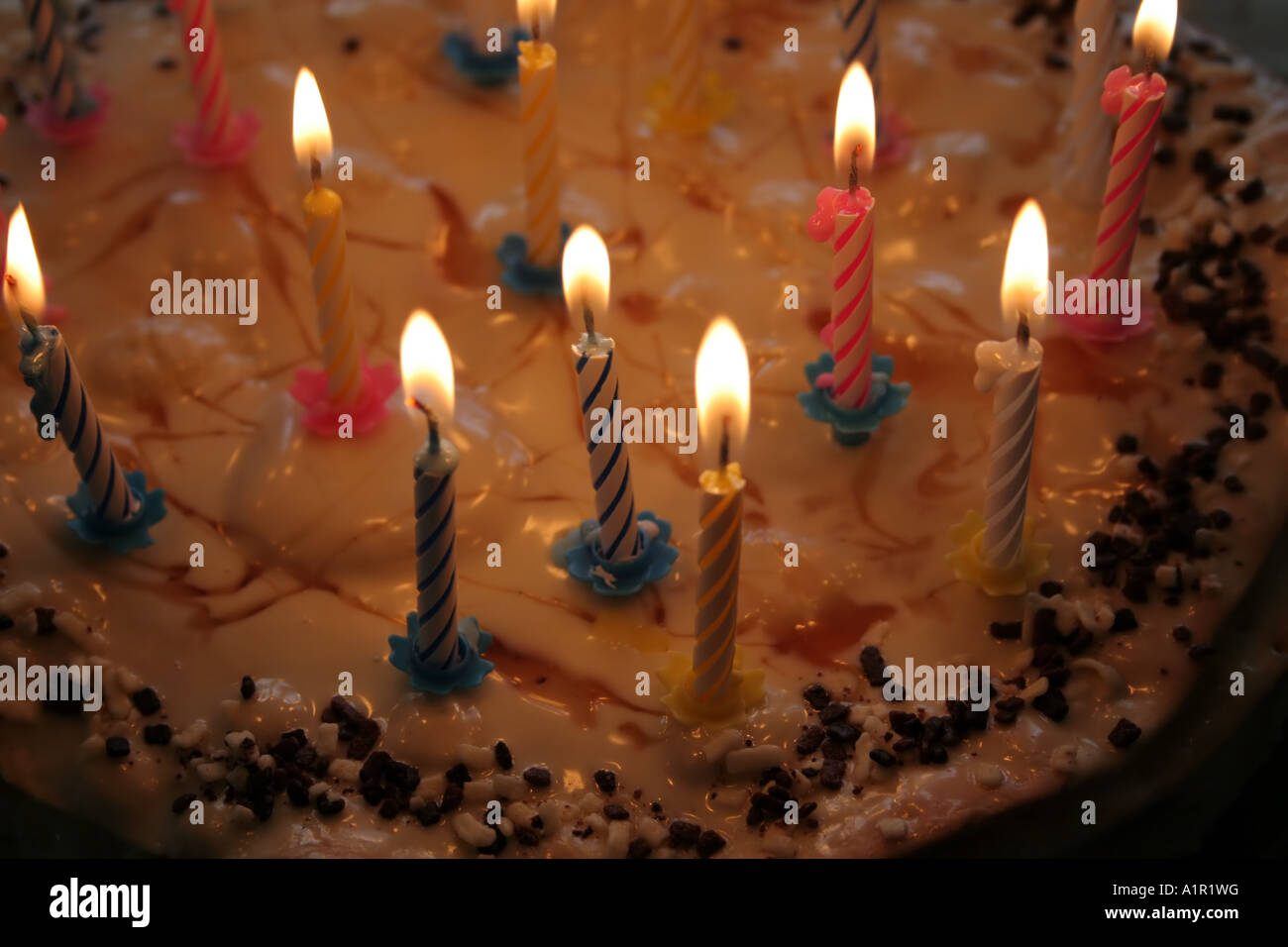 Gâteau d'anniversaire avec bougies allumées, garniture de caramel et saupoudrées de chocolat. Banque D'Images