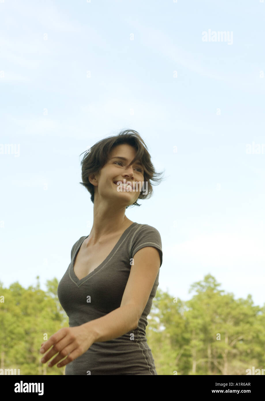 Woman walking outdoors, smiling, arbres en arrière-plan Banque D'Images