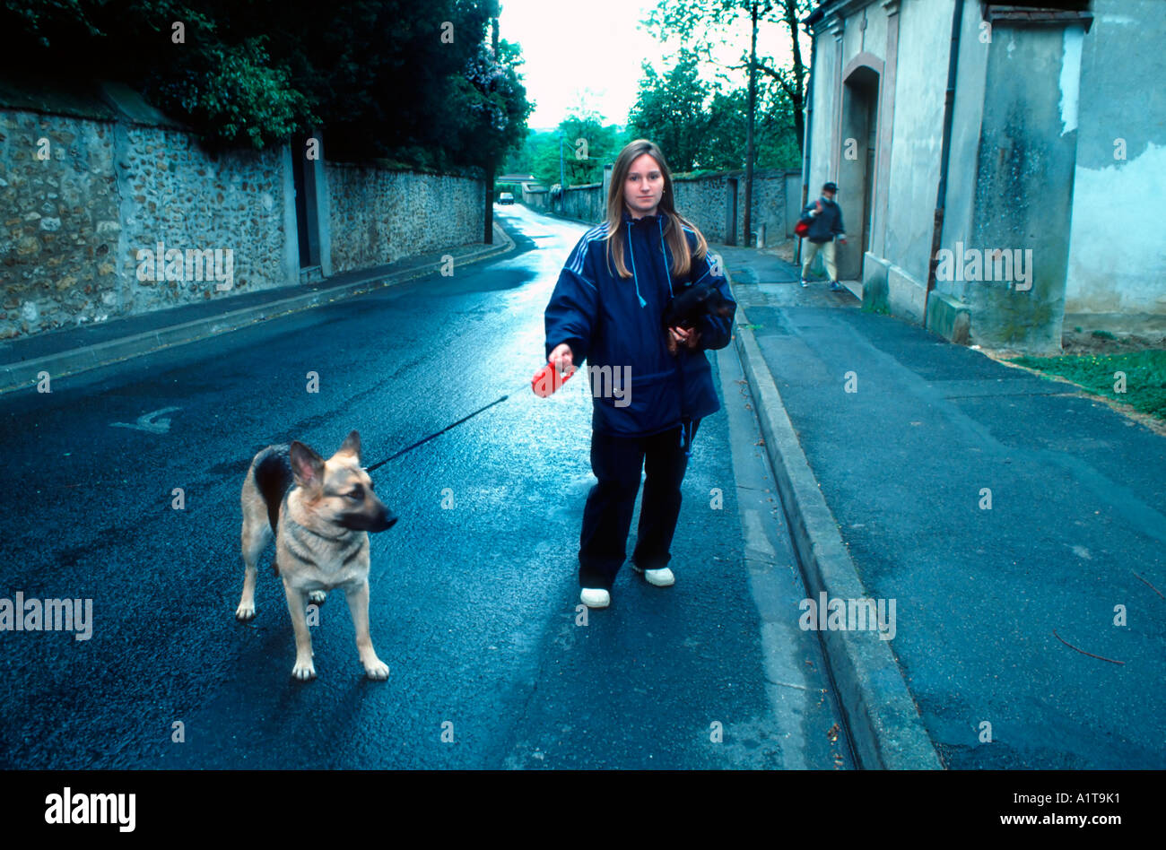 Paris France, jeune française Teen, chien de marche, après l'école Job sur la rue, seule attente en plein air, pluie, rue de banlieue, emplois d'adolescents Banque D'Images