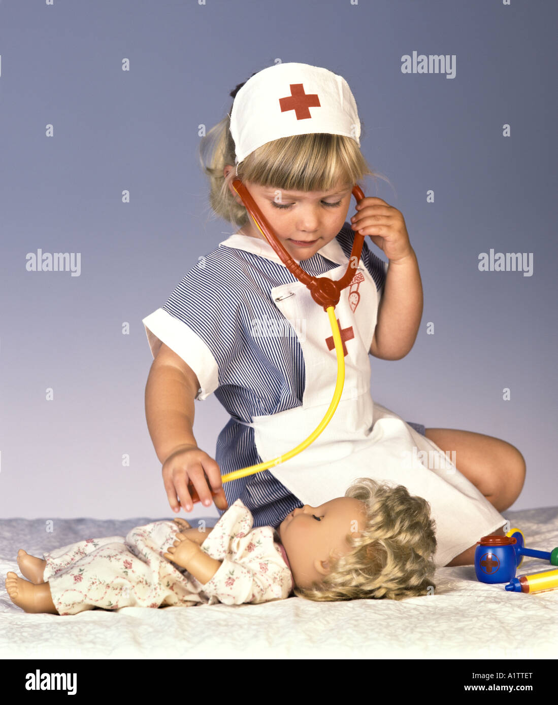 Une jeune fille dans un costume infirmières joue avec sa poupée et un stéthoscope Banque D'Images