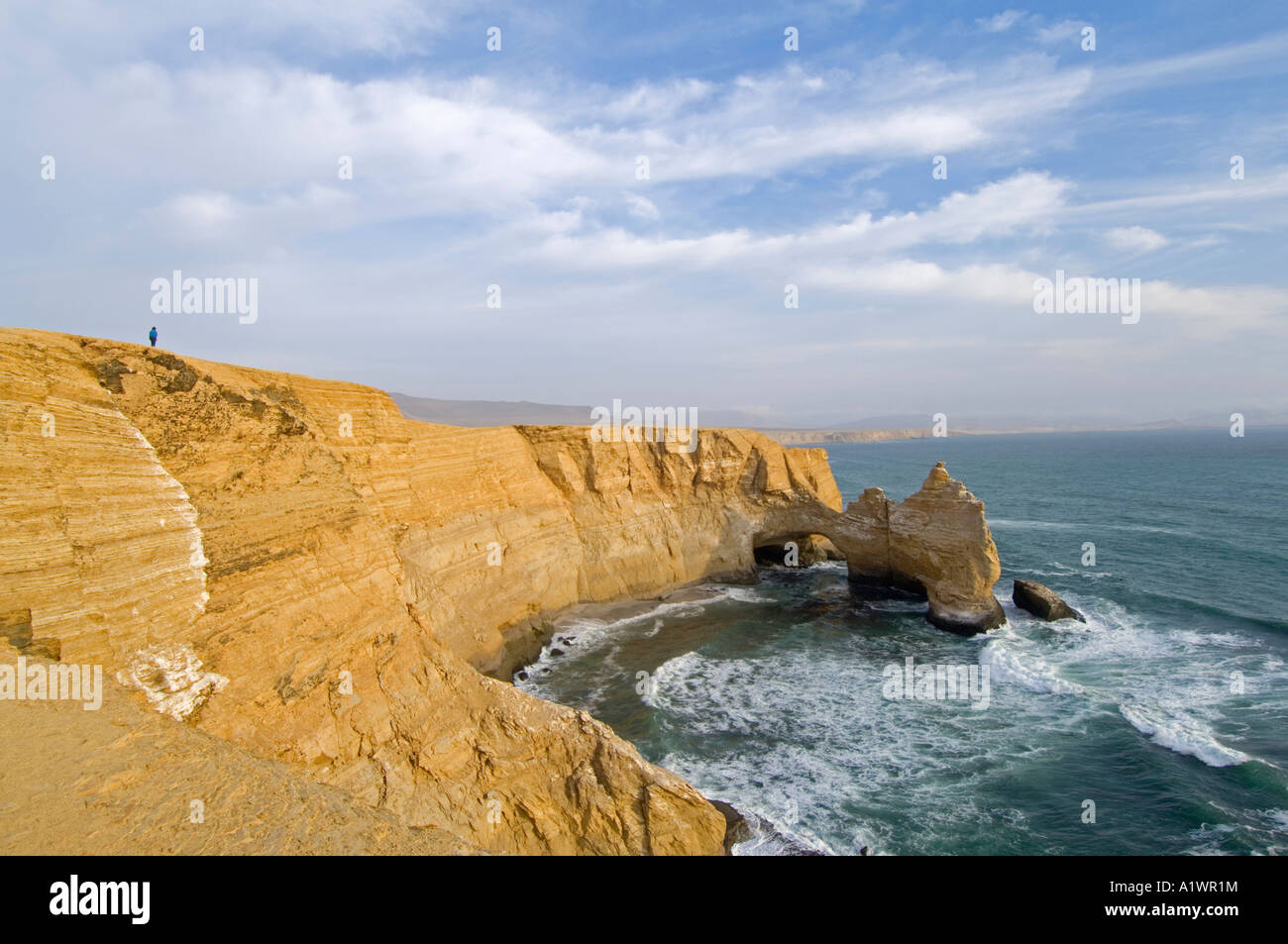 Un touriste est éclipsé par une zone de la côte et rocher connu sous le nom de 'La Cathédrale' dans la réserve nationale de Paracas. Banque D'Images