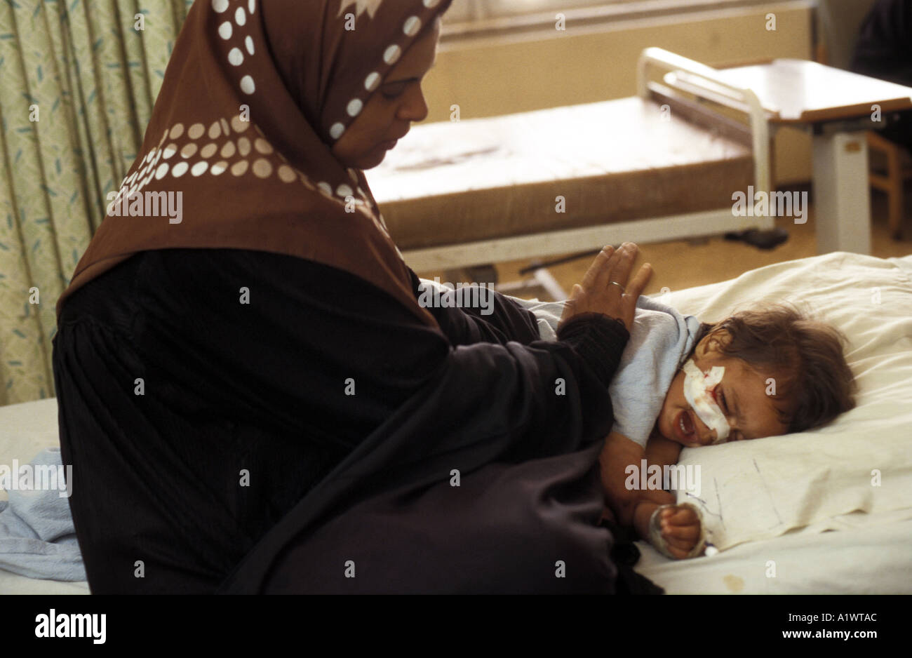 Le confort d'une mère son enfant blessé par des éclats de bombe cluster.Bagdad, Iraq Banque D'Images