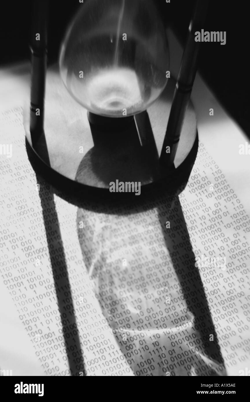 Un sablier sablier avec du sable temps qui passe de l'ombre et de papier et d'un code binaire Banque D'Images