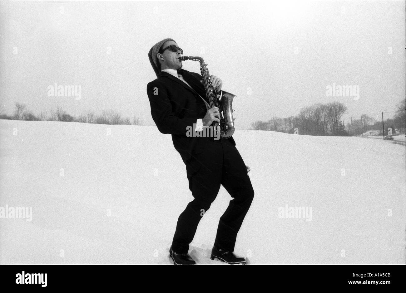 L'homme à jouer du saxophone dans une tempête de neige Winter blues concept drôle wearing Christmas holiday hat Banque D'Images