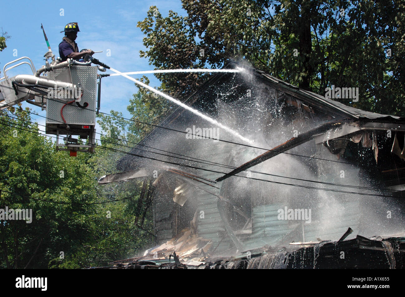 Les pompiers de pulvériser une maison la lutte contre l'incendie un incendie d'un camion échelle Banque D'Images