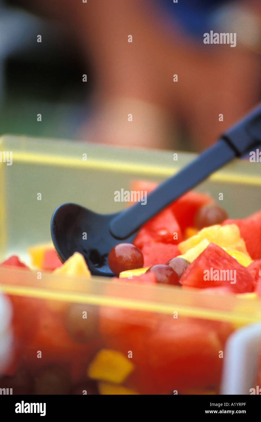 Close up detail cuillère en plastique de la salade de fruits melon melon raisin ananas tranches Banque D'Images