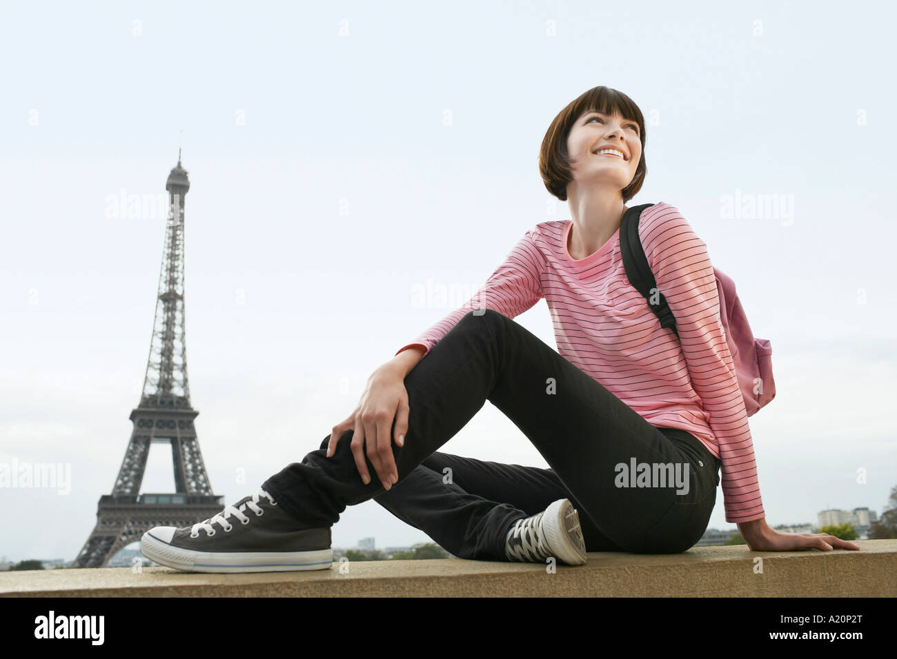 France, Paris, young woman sitting on balcon en face de la Tour Eiffel Banque D'Images