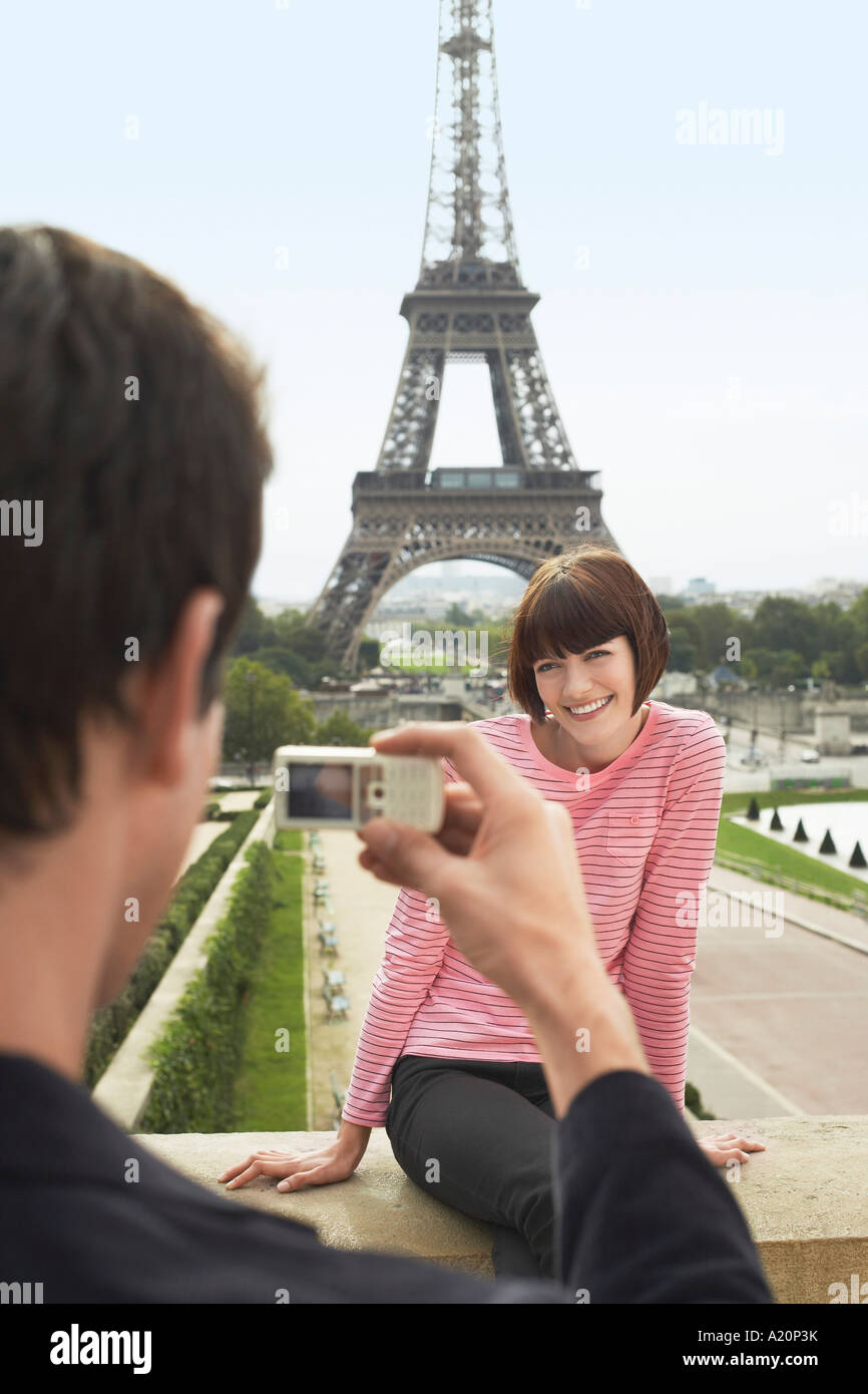 France, Paris, Man photographing woman in front of Eiffel Tower Banque D'Images